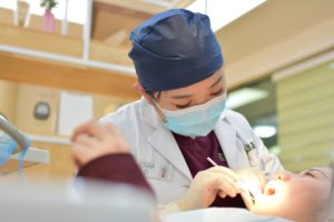 female doctor doing dental on girl lying on bed