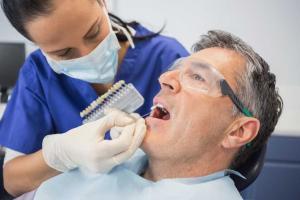 Cosmetic Dentist working on Man's Mouth