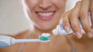 Person applying toothpaste to a toothbrush for oral hygiene.