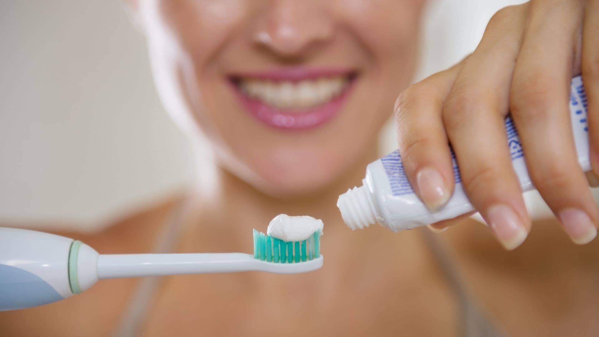 Person applying toothpaste to a toothbrush for oral hygiene.