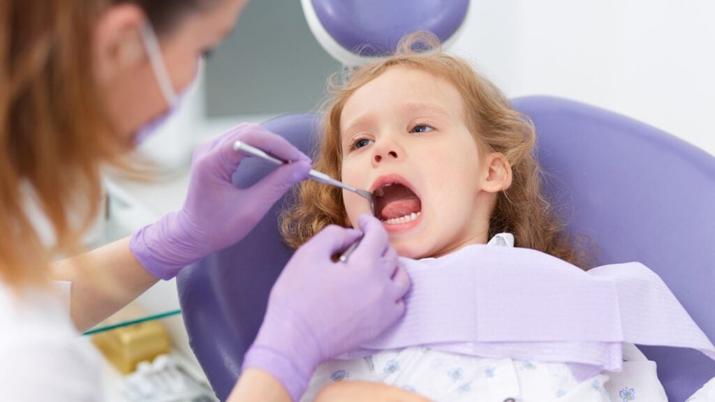 Child receiving dental examination from a dentist in a clinic setting.